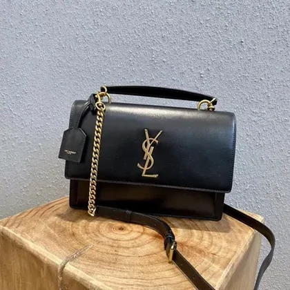 Black chain-strap bag on a wooden display block