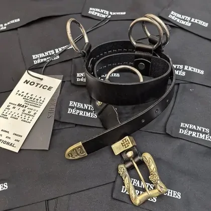 Black belts with metal buckles displayed on dark fabric